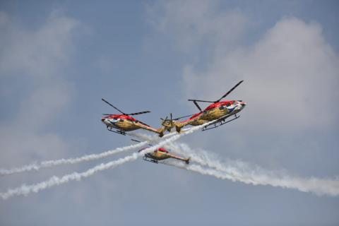 The Indian Air Force Sarang helicopter display team performs aerobatic maneuvers on the third day of Aero India 2021.