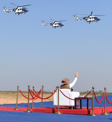 Prime Minister Narendra Modi waves at the helicopters during the inauguration of Aero India 2023.